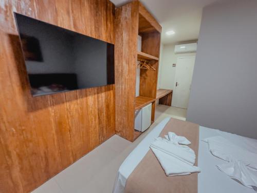 a room with a bed with a television on a wall at Pousada Porto Girassol in Abraão