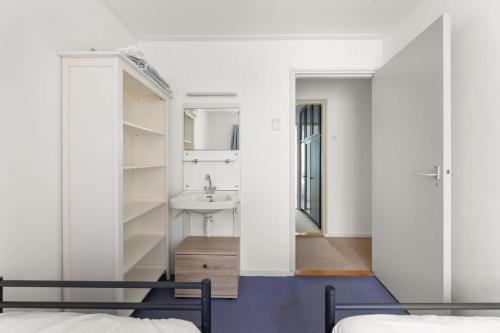 een slaapkamer met een wastafel en een spiegel bij Hello Zeeland - Vakantiehuis Weststraat 13A in Domburg