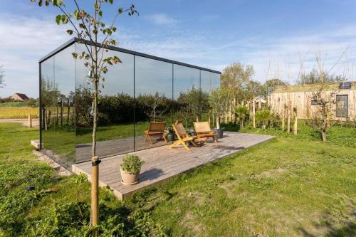 a patio with two chairs and a table in a yard at ÖÖD Sunrise at Buitenplaats Zeeuwse Liefde in Westkapelle