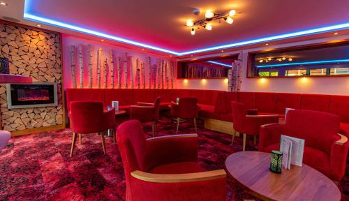 a restaurant with red chairs and tables and a fireplace at Wellnesshotel Hohenrodt in Loßburg