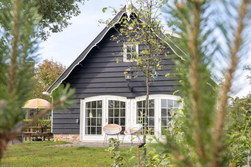 a black cottage with two chairs in the yard at De Kleine Schuur at Buitenplaats Zeeuwse Liefde in Westkapelle