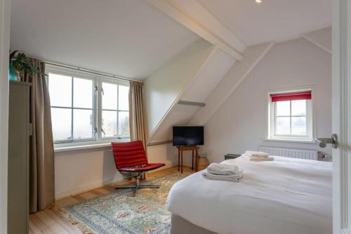 a bedroom with a bed and a red chair at De Kleine Schuur at Buitenplaats Zeeuwse Liefde in Westkapelle