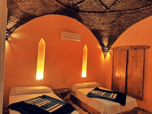 2 camas en una habitación con pared de color naranja en فيلا شمس تونس, en Tunis