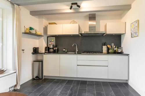 a kitchen with white cabinets and a tile floor at Het Kleine Huis at Buitenplaats Zeeuwse Liefde in Westkapelle