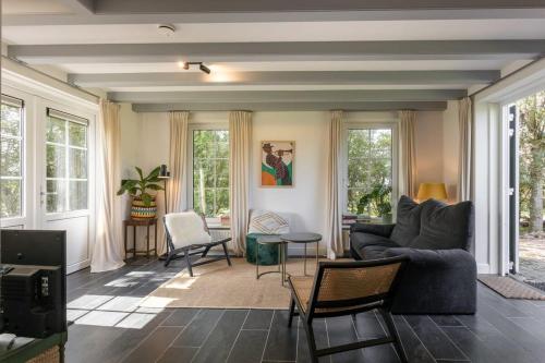 a living room with a couch and chairs and windows at Het Kleine Huis at Buitenplaats Zeeuwse Liefde in Westkapelle