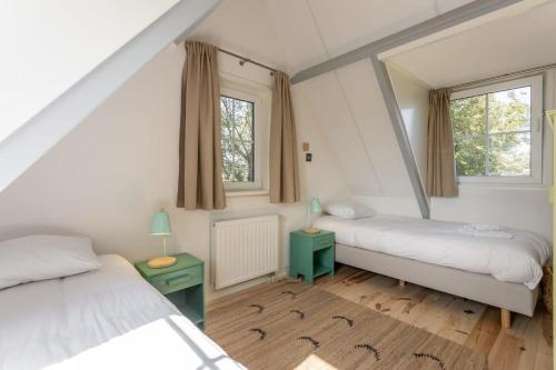 a bedroom with two beds and a mirror at Het Kleine Huis at Buitenplaats Zeeuwse Liefde in Westkapelle