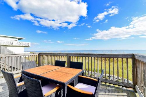 a wooden table and chairs on a balcony with the ocean at HAZELS CHILD II Beach House DIRECT OCEANFRONT Ocean and Pier Views in Myrtle Beach
