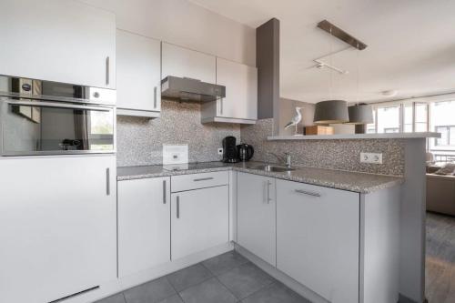 a white kitchen with white cabinets and appliances at Hello Zeeland - Duinhof V 1-7 in Cadzand
