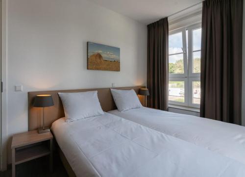 1 Schlafzimmer mit 2 weißen Betten und einem Fenster in der Unterkunft Hello Zeeland - Duinhof V 1-7 in Cadzand