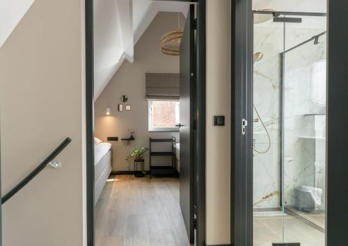 - un couloir avec une porte en verre menant à une salle de bains dans l'établissement Hello Zeeland - Vakantiehuis Herenstraat 1A, à Domburg