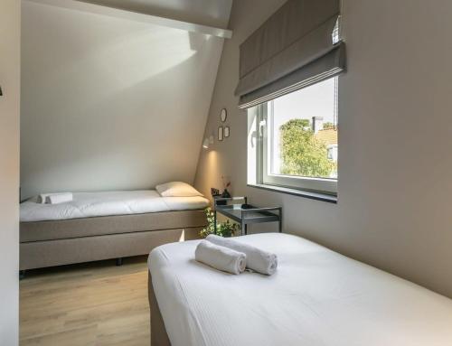 a small bedroom with two beds and a window at Hello Zeeland - Vakantiehuis Herenstraat 1A in Domburg