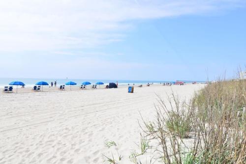 a beach with umbrellas and people on the beach at Anchor Down Luxury Ocean View Beach House w Pool in Myrtle Beach