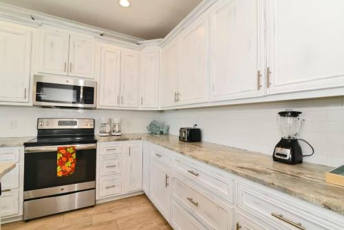 a kitchen with white cabinets and a stove top oven at Anchor Down Luxury Ocean View Beach House w Pool in Myrtle Beach