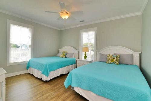 a bedroom with two beds and a ceiling fan at Anchor Down Luxury Ocean View Beach House w Pool in Myrtle Beach