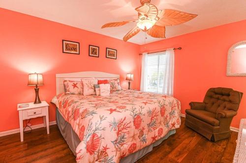 een slaapkamer met oranje muren en een bed en een stoel bij Island Breeze Pet Friendly Bungalow w Pool in Myrtle Beach