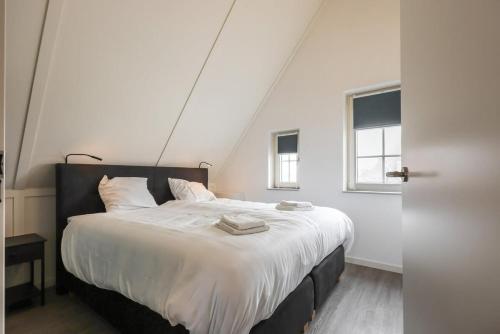 a bedroom with a large bed with white sheets at Hello Zeeland - vakantiewoning Knuitershoek 66 