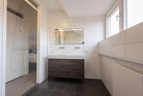 a bathroom with a tub and a sink and a mirror at Hello Zeeland - vakantiewoning Knuitershoek 66 