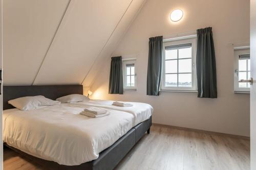 1 dormitorio con 1 cama grande y 2 ventanas en Hello Zeeland - vakantiewoning Knuitershoek 102 