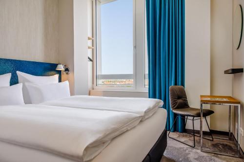 a hotel room with a bed and a window at Motel One München-Campus in Munich