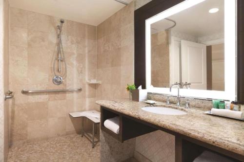 a bathroom with a sink and a mirror and a shower at Hilton Los Angeles/San Gabriel in San Gabriel