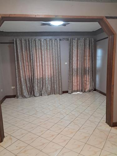 Habitación vacía con cortinas y suelo de baldosa. en ZET HOLDINGS, en Jinja
