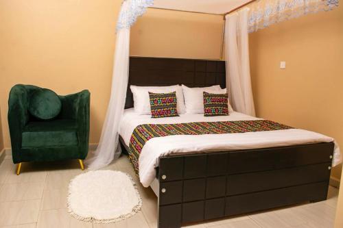 a bedroom with a bed and a green chair at ZET HOLDINGS in Jinja