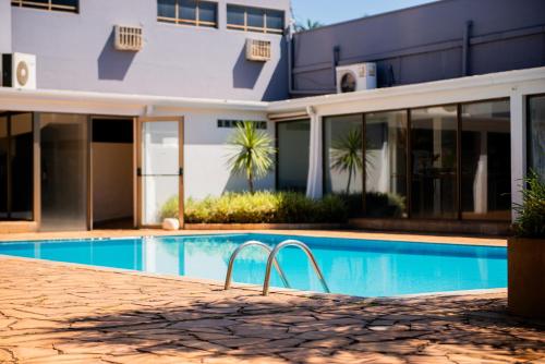 a swimming pool in front of a house at Hotel Fernandão in Pouso Alegre