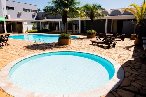 una piscina en un complejo con mesas y sillas en Hotel Fernandão, en Pouso Alegre