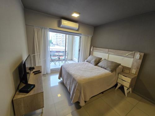 een slaapkamer met een bed, een televisie en een balkon bij Maipu y Avda. Pellegrini in Rosario