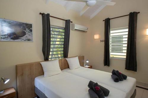 a bedroom with two beds and two windows at Caracara D1 Relax & Dive Resort Bonaire Village in Kralendijk