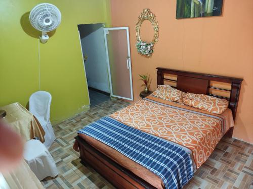1 dormitorio con cama, ventilador y espejo en Cabañas Horeb, en Tena