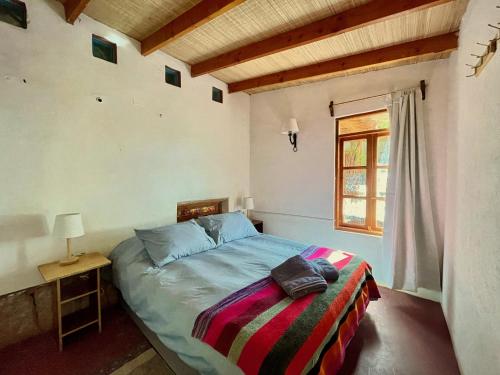 um quarto com uma cama e uma janela em Casa Adobe - tranquilidad en el Desierto de Atacama em San Pedro de Atacama