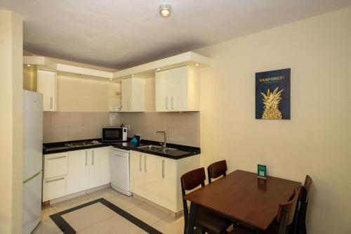 een keuken met witte kasten en een tafel en een eetkamer bij Caracara M4 Relax & Dive Resort Bonaire Village in Kralendijk