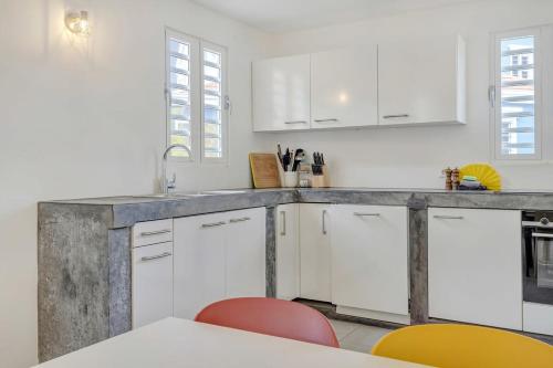a kitchen with white cabinets and red chairs at Casa Leeward with Pool on the Laguna Marina in Kralendijk