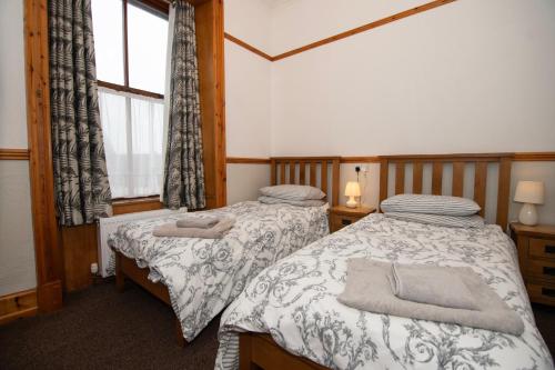 two twin beds in a room with a window at Alder Lodge Guest House in Lerwick