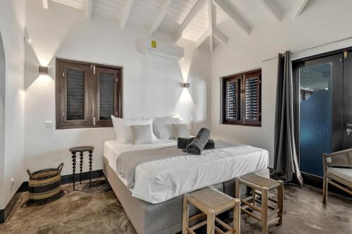 ein weißes Schlafzimmer mit einem Bett und zwei Stühlen in der Unterkunft Costa de la Luz on the water of the Laguna Marina in Kralendijk