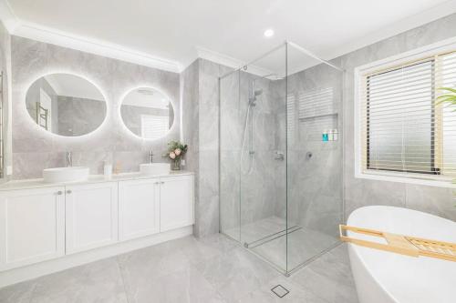 ein Bad mit einer Dusche, 2 Waschbecken und einem WC in der Unterkunft Pool Sauna Cinema Office Room 4BR Spacious house in Gold Coast