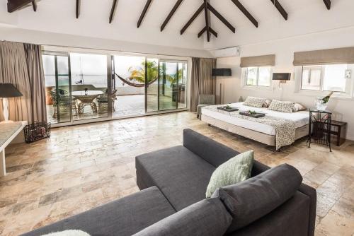 ein Wohnzimmer mit einer Couch und einem Bett in der Unterkunft Nirvana Lodge with Private Pool and House Reef in Kralendijk