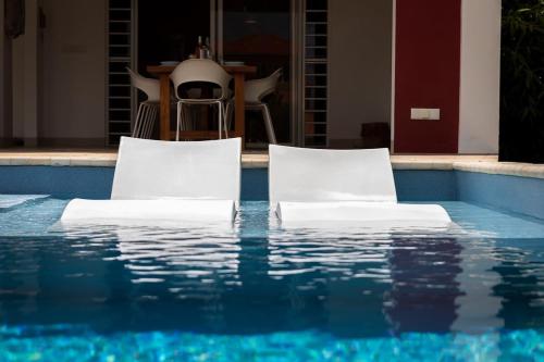 two white chairs sitting next to a swimming pool at Kas Dive-In with Private Pool on the Laguna Marina in Kralendijk