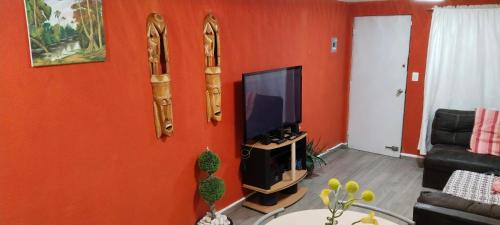 sala de estar con paredes de color naranja y TV de pantalla plana. en Llegaste a casa almendros, en Santa Cruz Tecamac