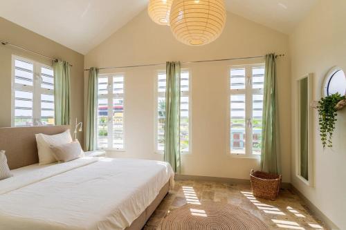 a bedroom with a large bed with windows and a chandelier at Kas Dive-In with Private Pool on the Laguna Marina in Kralendijk