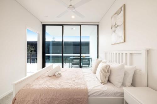 a white bedroom with a bed with a laptop on it at B-A Altura 81003 in Brisbane