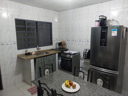 a kitchen with a table with a plate of fruit on it at Quarto disponível para temporada da Agrishow in Ribeirão Preto
