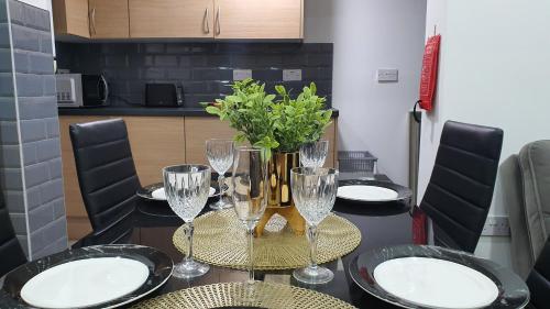 a table with glasses and a vase with flowers on it at Highfield House in Wellingborough