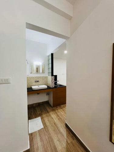 a bathroom with white walls and wooden floors and a sink at Melvet Residency in Cochin
