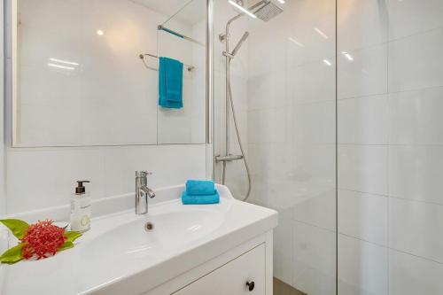 uma casa de banho branca com um lavatório e um chuveiro em Port Bonaire Oasis A701 with Sea View em Kralendijk