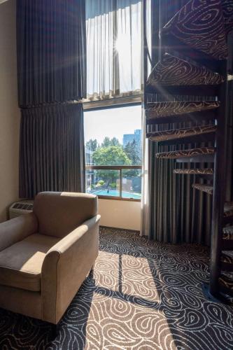 a living room with a chair and a large window at Hotel 116, A Coast Hotel Bellevue in Bellevue