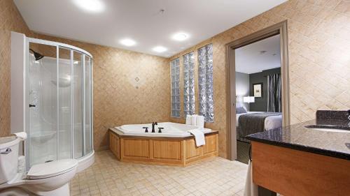 a bathroom with a tub and a shower and a toilet at Best Western Plus Woodstock Hotel Conference Centre in Woodstock