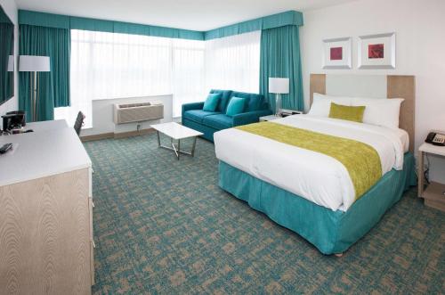 a hotel room with a large bed and a blue couch at Coast Hotel & Convention Centre in Langley