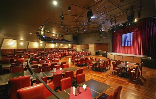 Coast Hotel & Convention Centre في لانغلي: صالة طعام بها طاولات وكراسي ومسرح